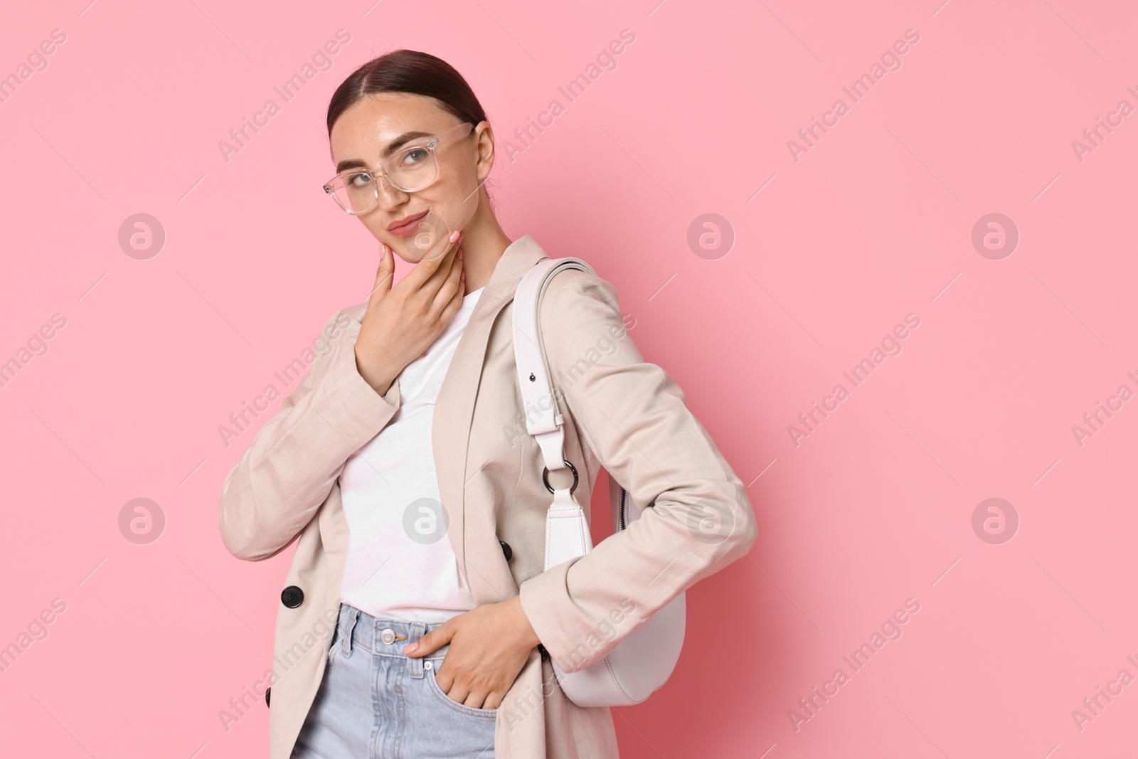 Photo of Stylish woman in beige jacket with bag on pink background, space for text