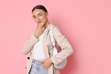 Stylish woman in beige jacket with bag on pink background, space for text