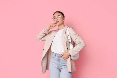 Stylish woman in beige jacket with bag on pink background