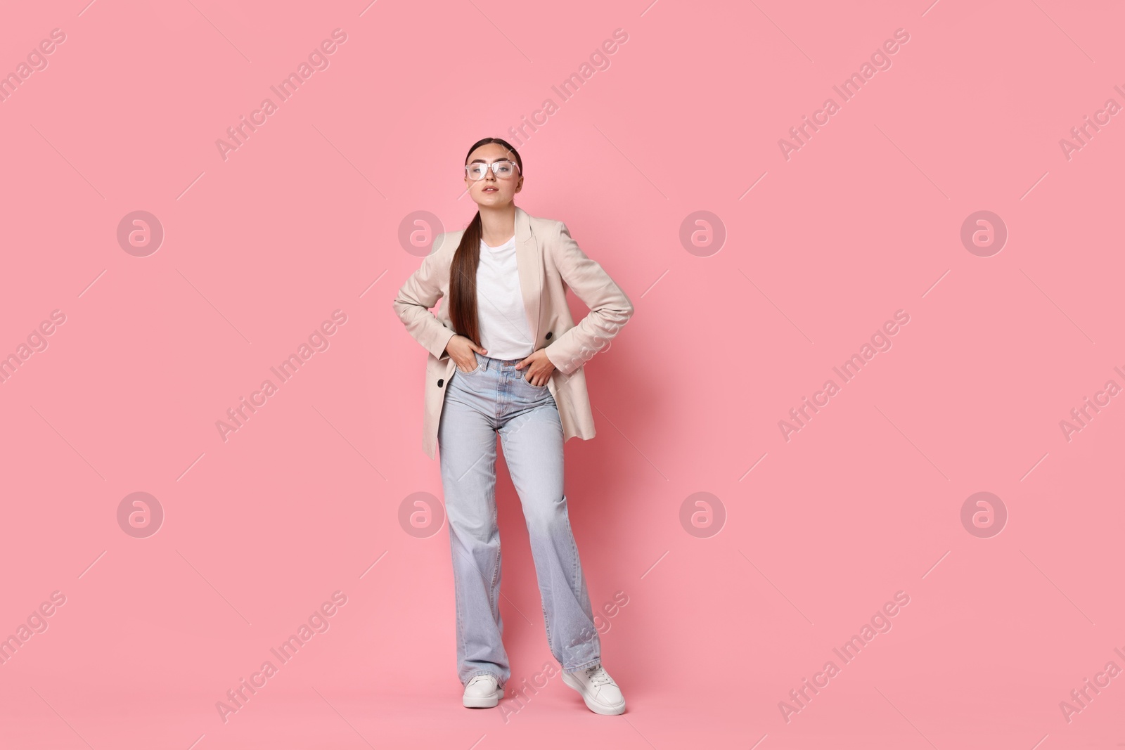 Photo of Stylish woman in beige jacket and jeans on pink background