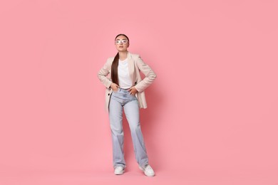 Stylish woman in beige jacket and jeans on pink background