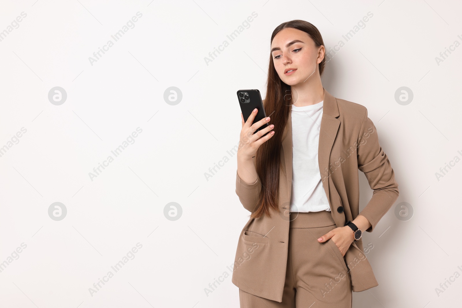 Photo of Woman in beige suit using smartphone on white background, space for text