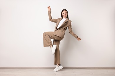 Photo of Beautiful woman in beige suit and white sneakers indoors