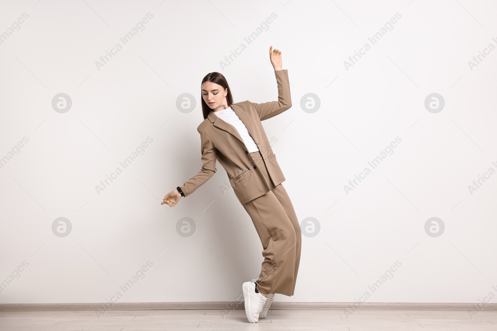 Photo of Beautiful woman in beige suit and white sneakers indoors