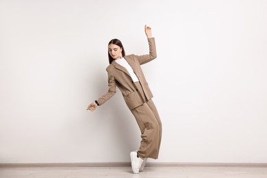 Beautiful woman in beige suit and white sneakers indoors