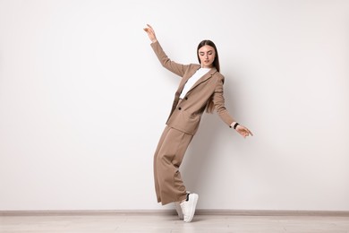 Beautiful woman in beige suit and white sneakers indoors