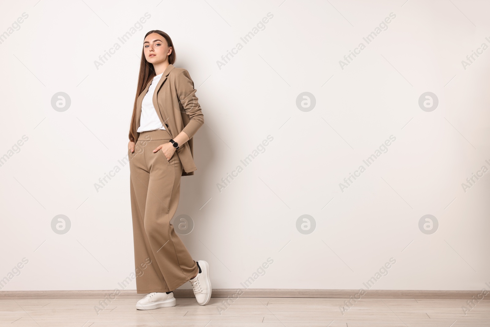 Photo of Beautiful woman in beige suit indoors, space for text