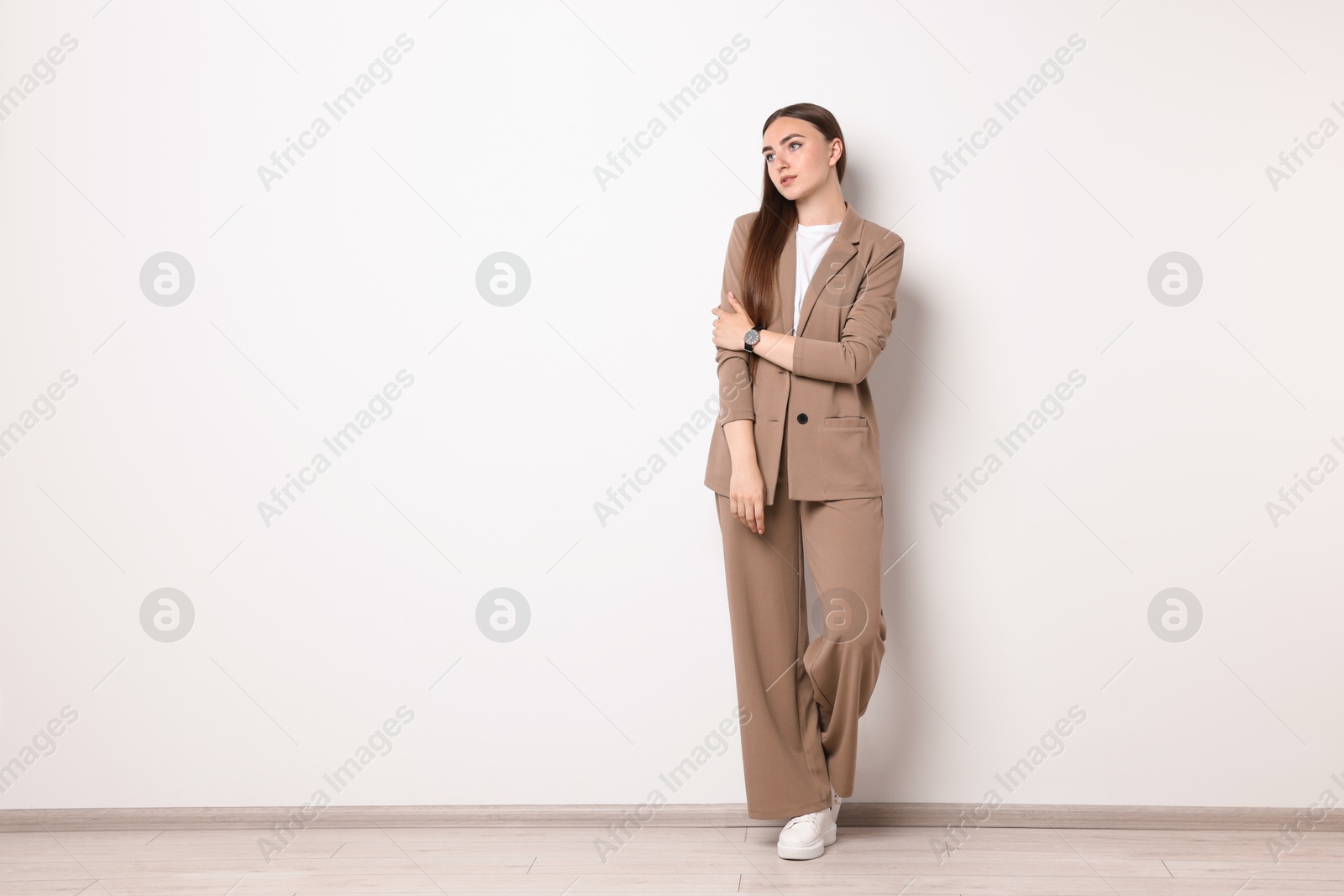 Photo of Beautiful woman in beige suit indoors, space for text