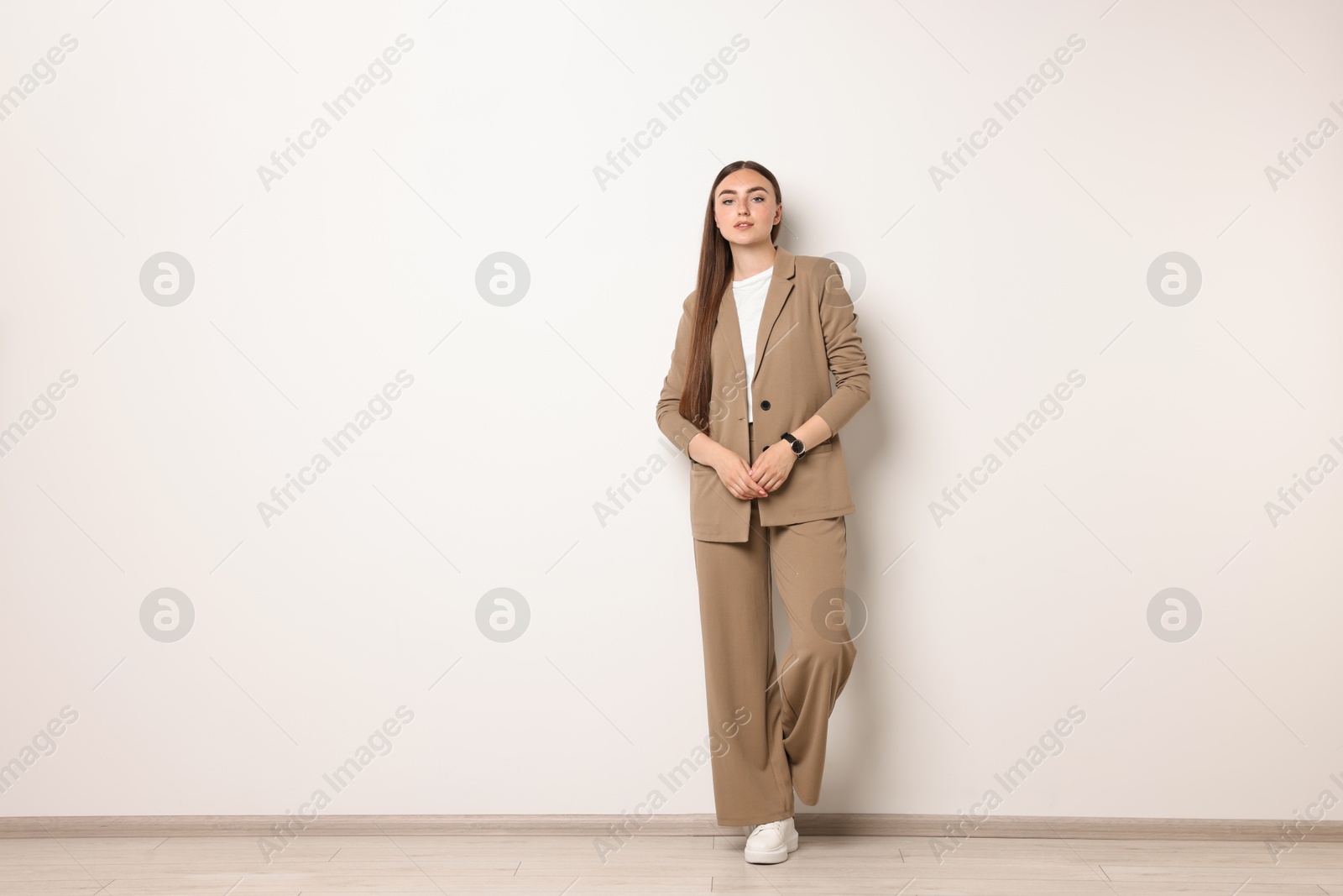 Photo of Beautiful woman in beige suit indoors, space for text