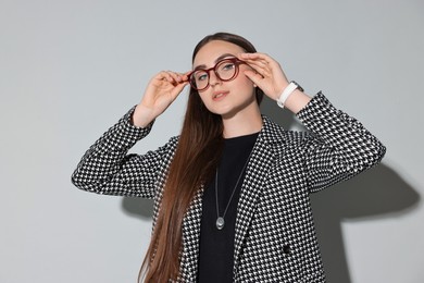 Photo of Beautiful woman in stylish suit and glasses on gray background