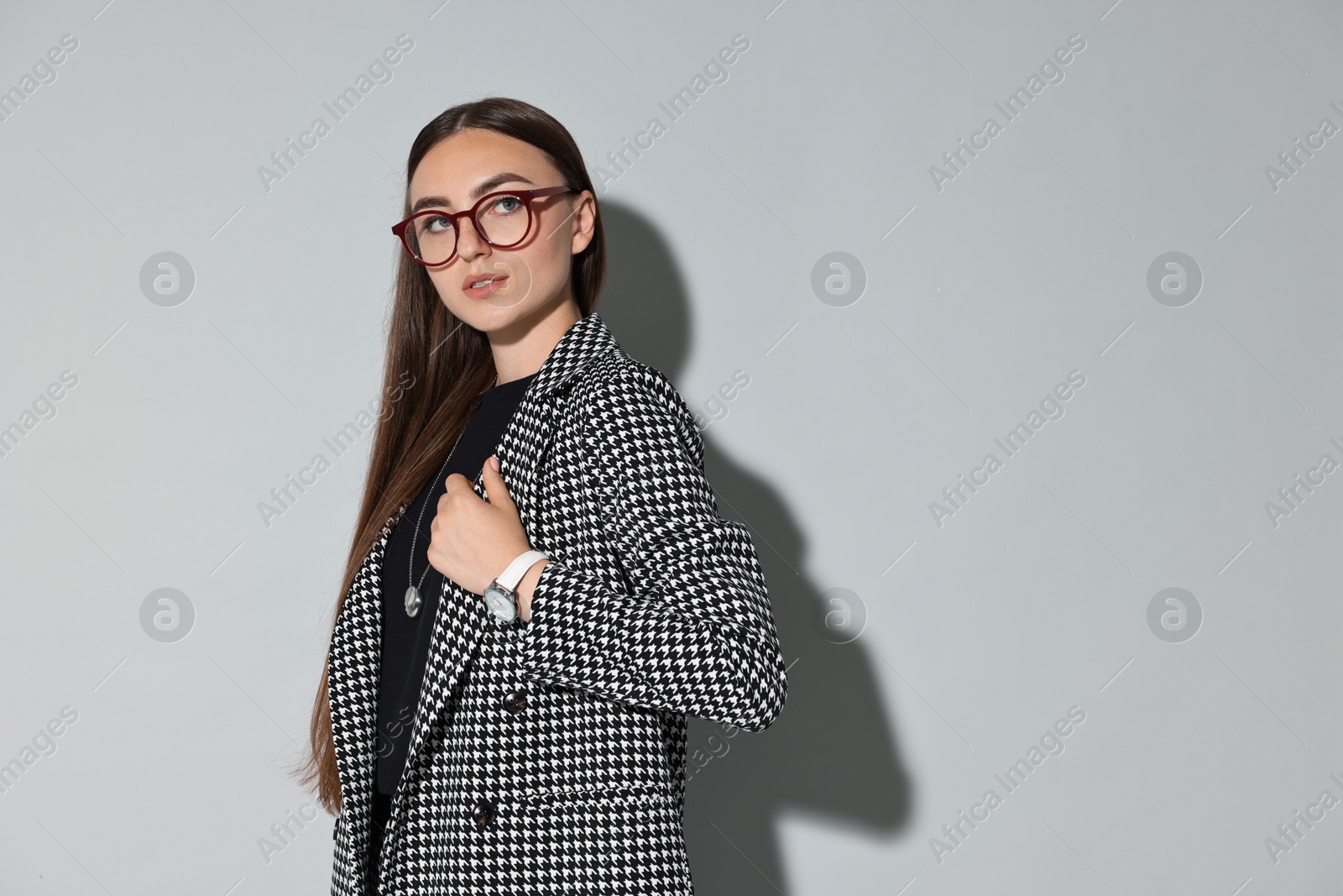 Photo of Beautiful woman in stylish suit and glasses on gray background, space for text