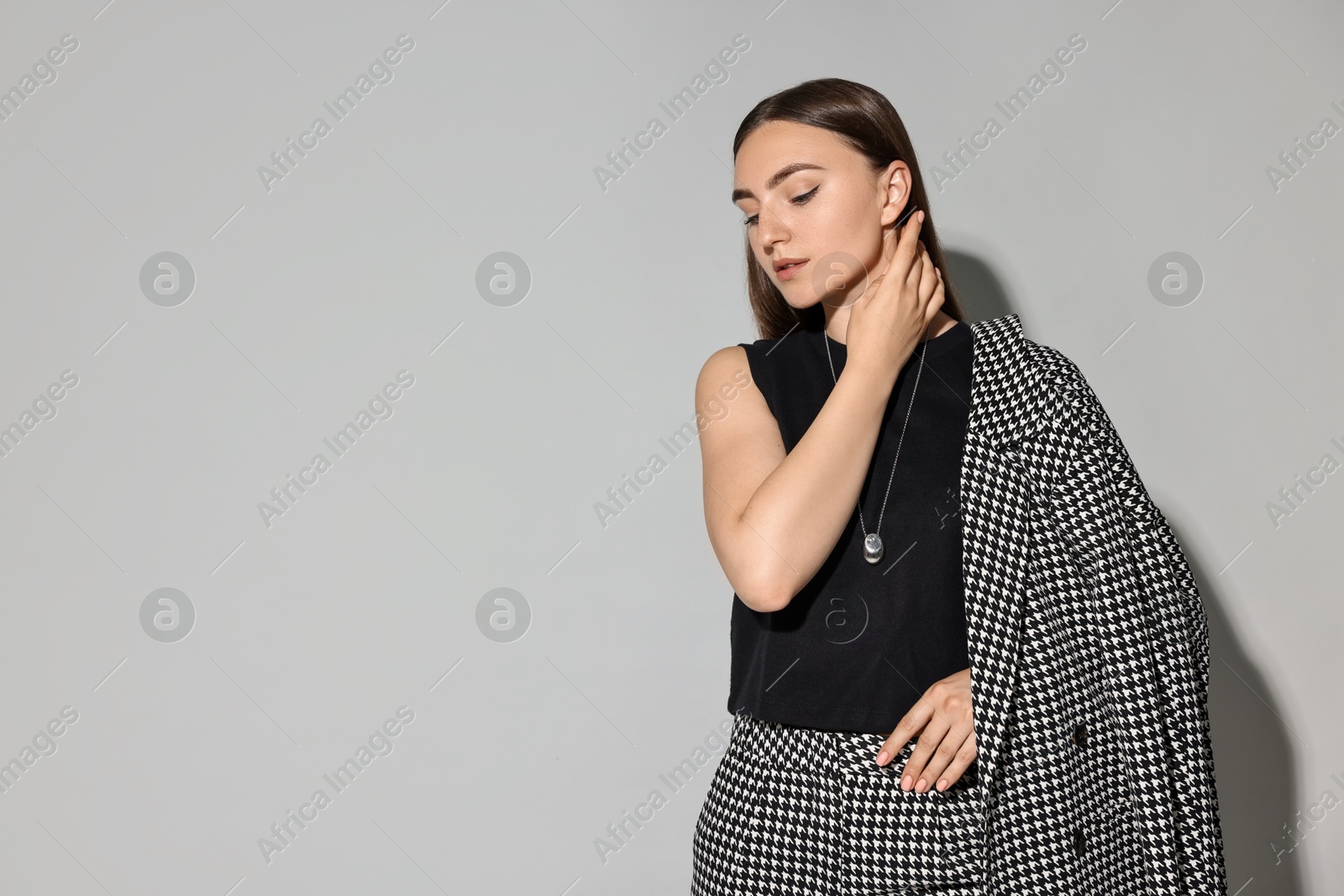 Photo of Beautiful woman in stylish suit on gray background, space for text