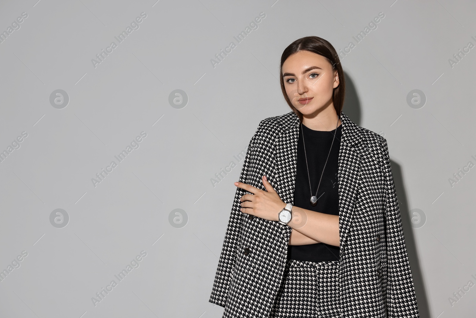 Photo of Beautiful woman in stylish suit on gray background, space for text