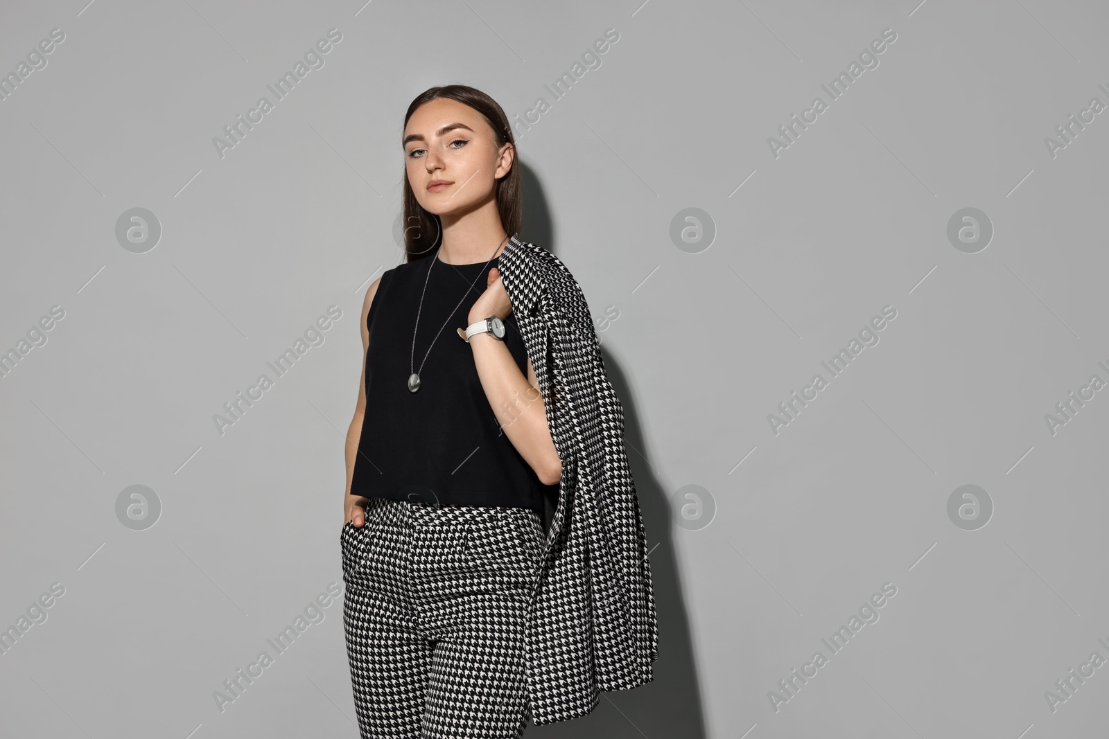 Photo of Beautiful woman in stylish suit on gray background, space for text