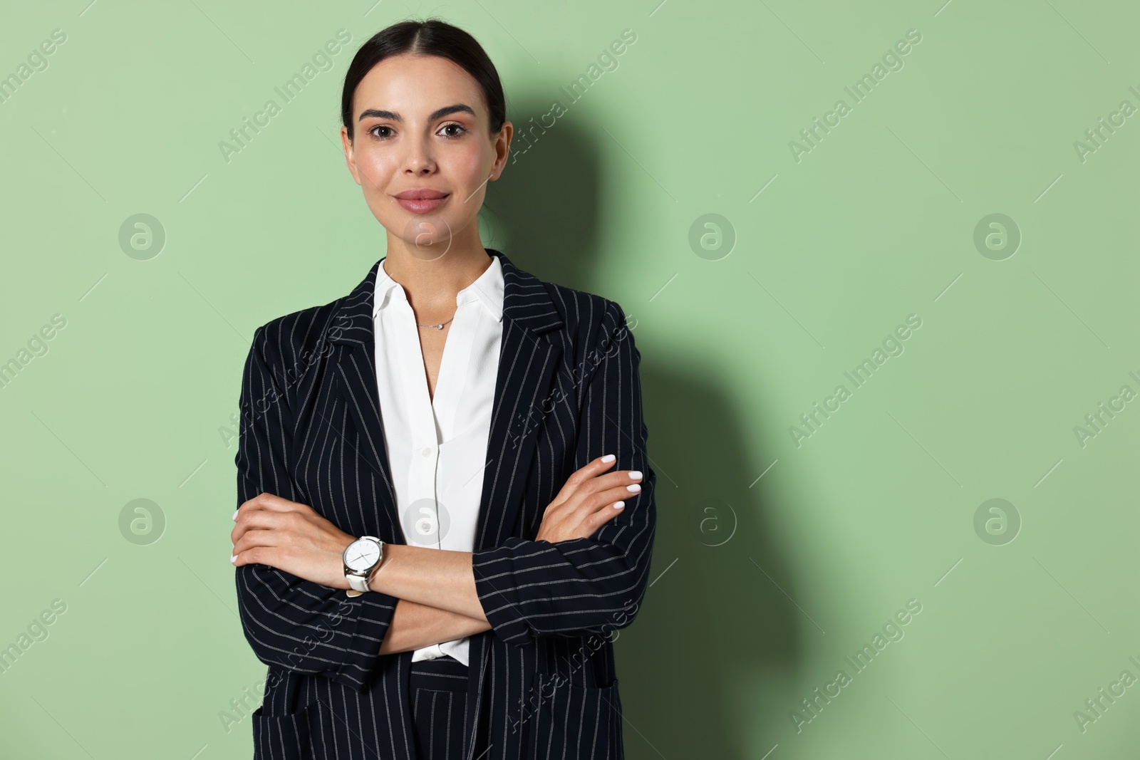 Photo of Beautiful woman in black striped suit on green background, space for text