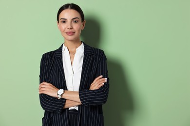 Beautiful woman in black striped suit on green background, space for text