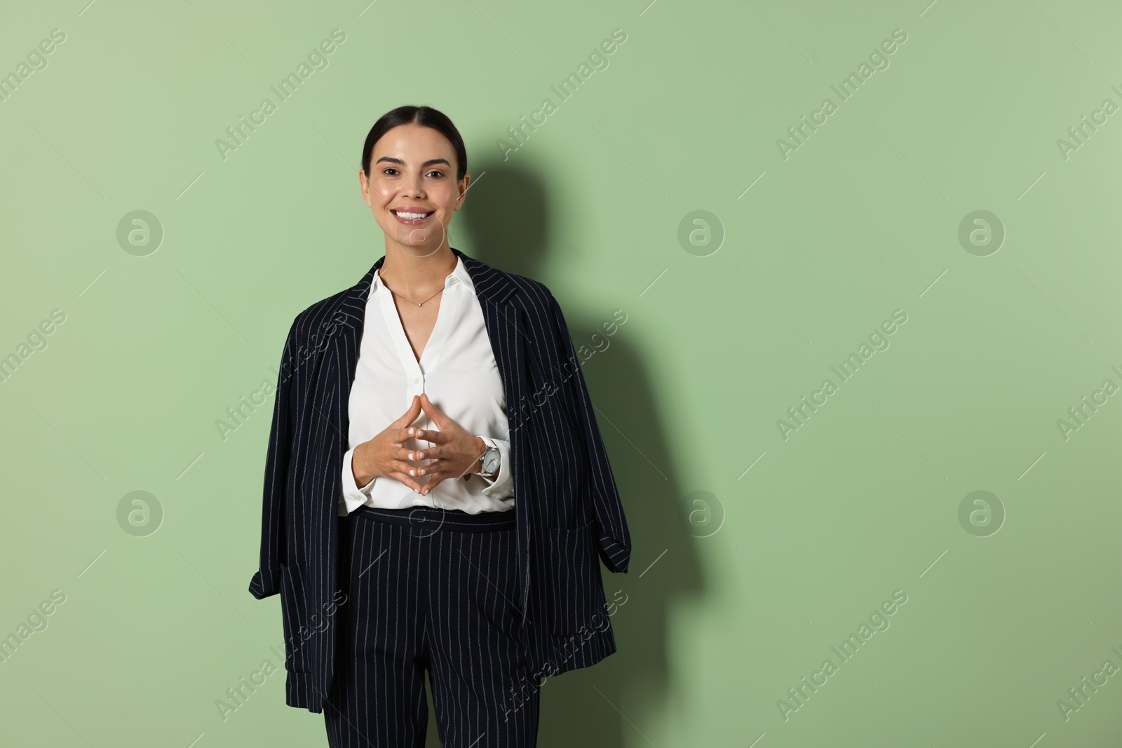 Photo of Beautiful woman in black striped suit on green background, space for text