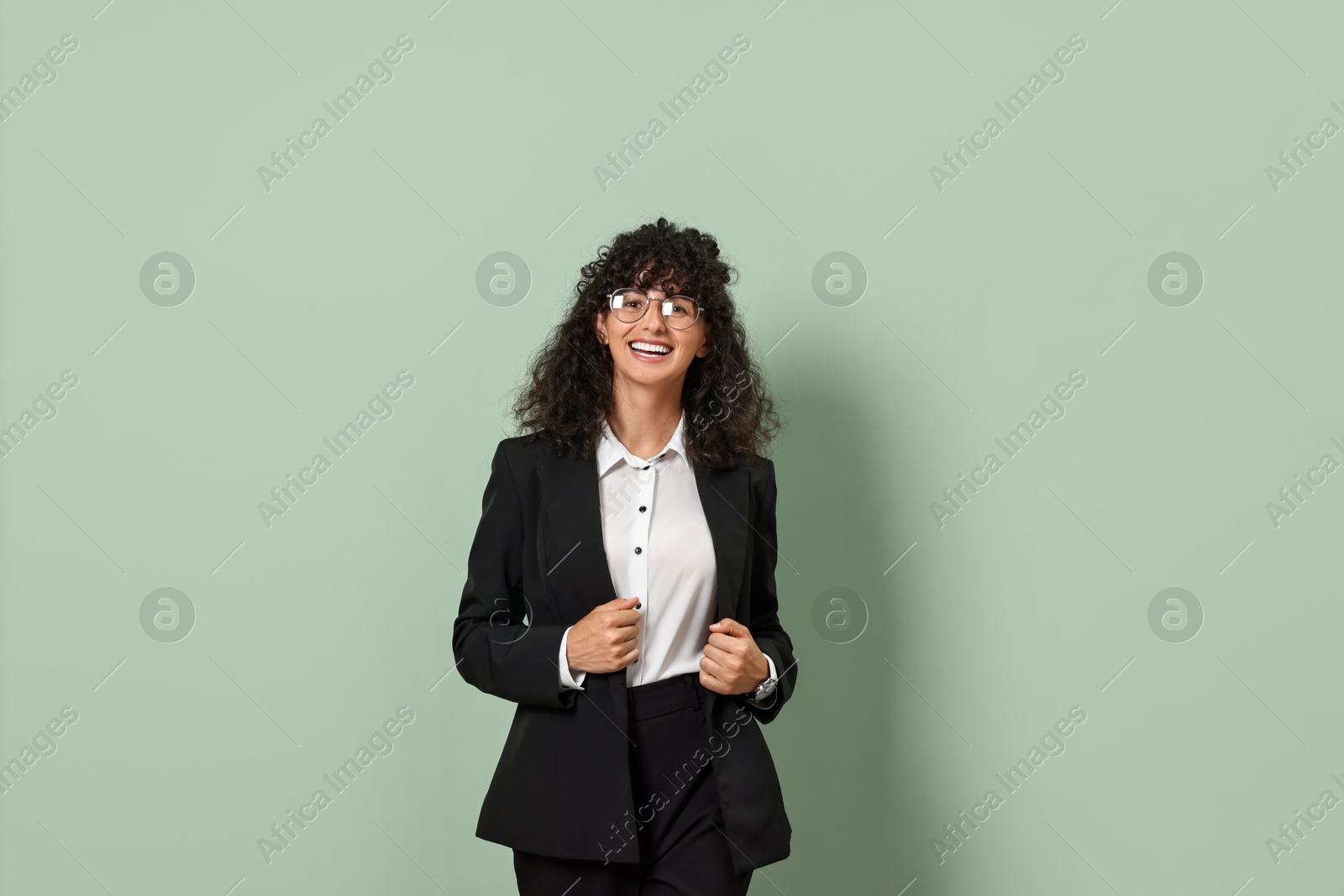 Photo of Beautiful young woman in stylish black suit on light olive background