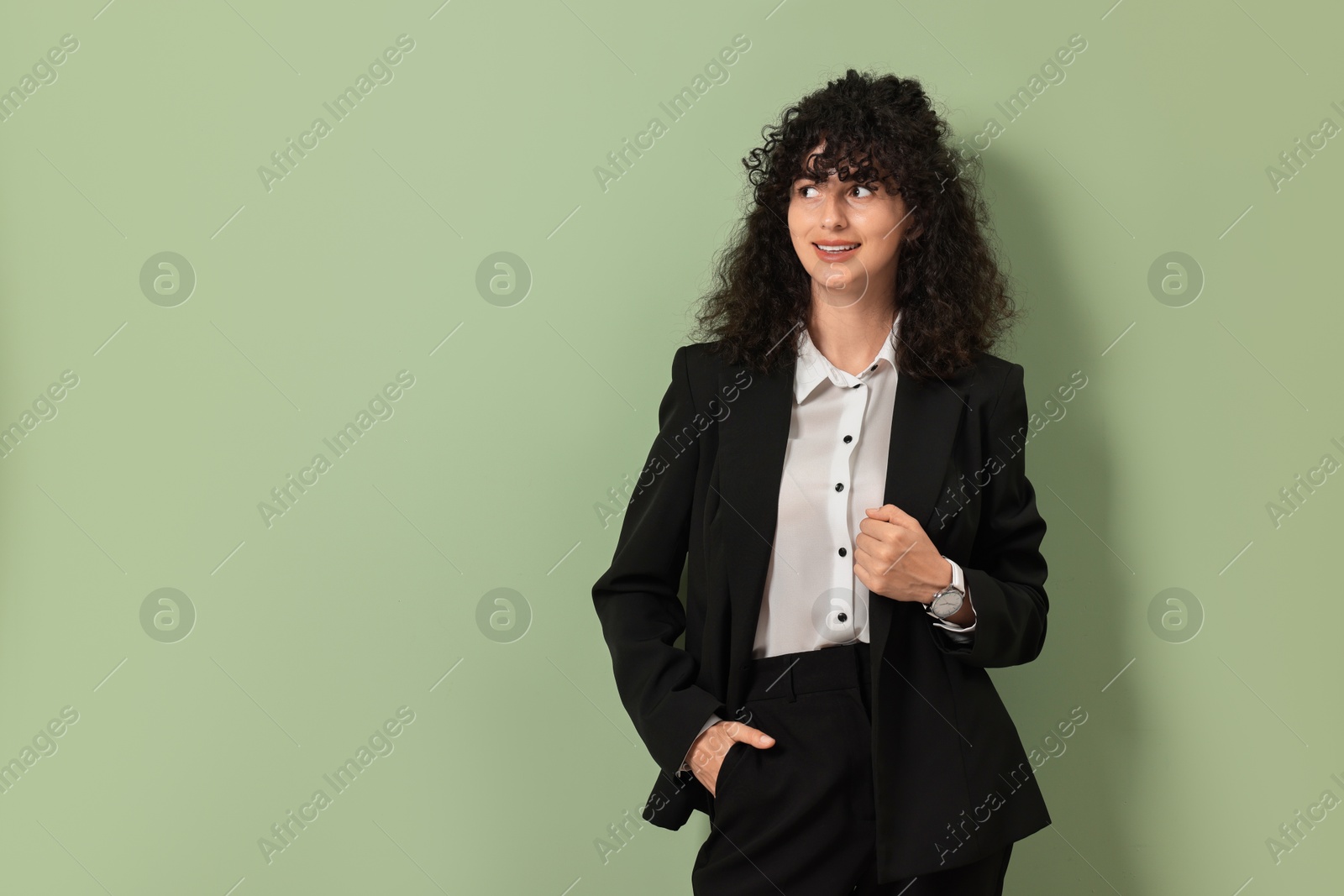 Photo of Beautiful young woman in stylish black suit on light olive background, space for text