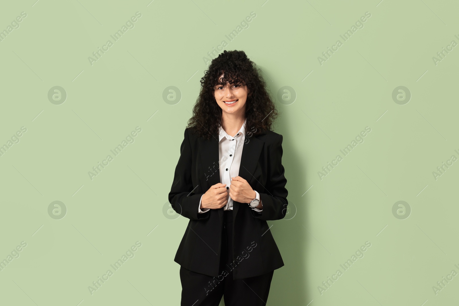 Photo of Beautiful young woman in stylish black suit on light olive background