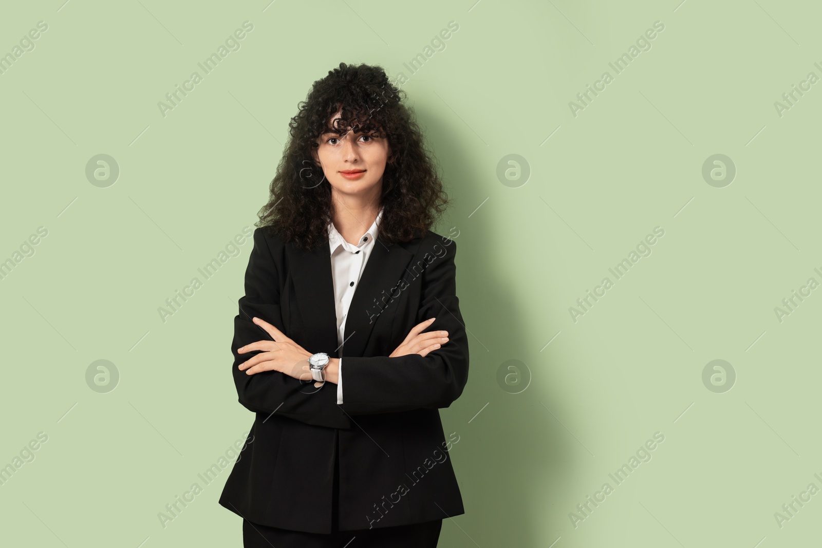 Photo of Beautiful young woman in stylish black suit on light olive background, space for text