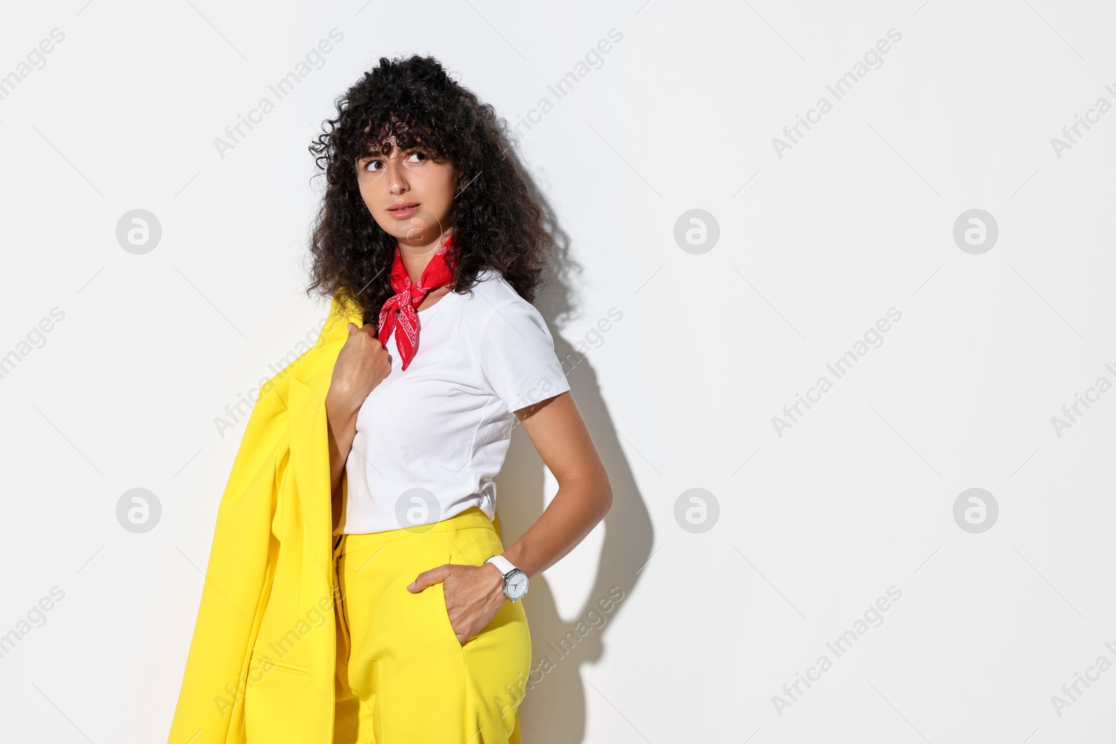 Photo of Beautiful young woman in stylish yellow suit on light background, space for text