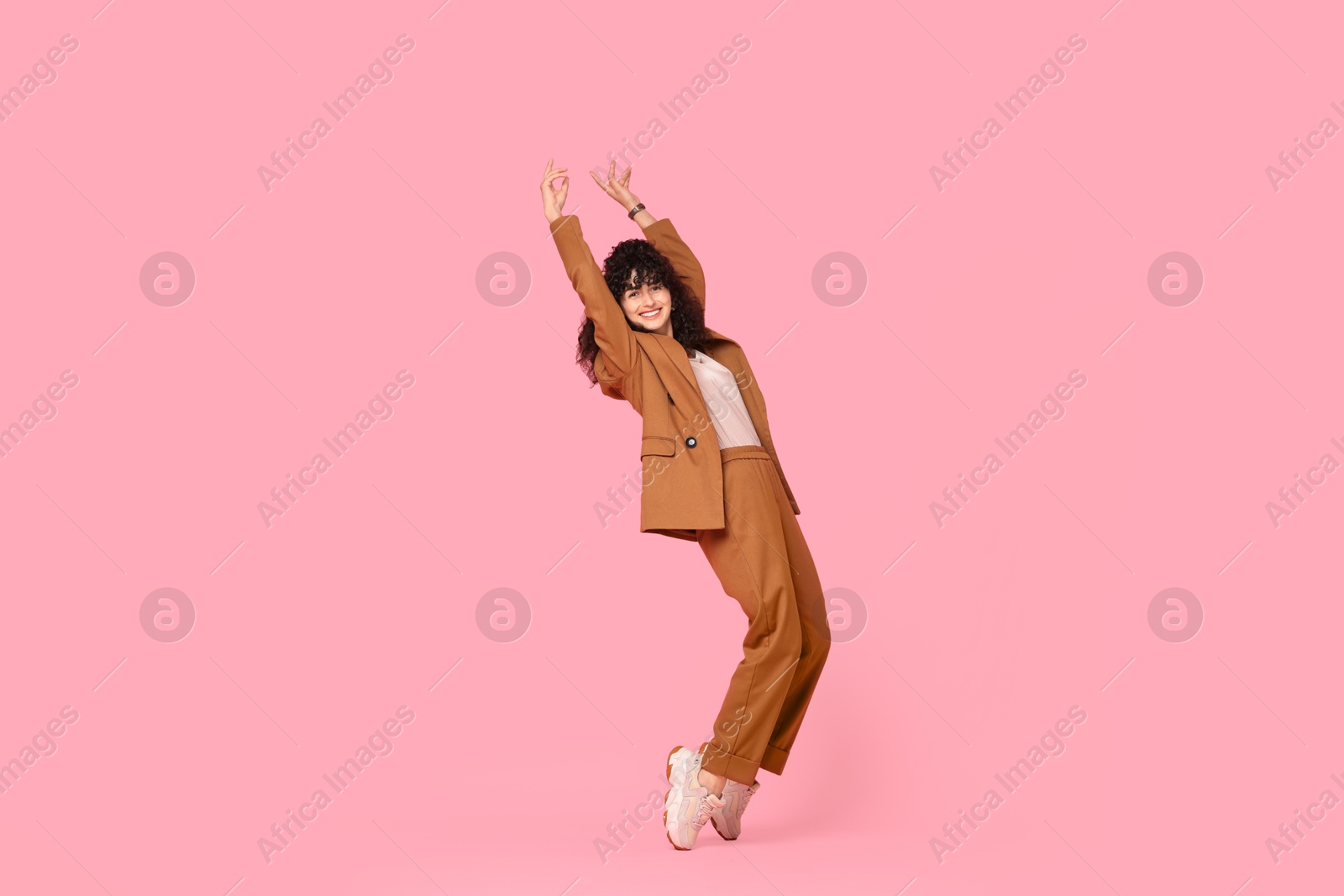 Photo of Beautiful young woman in stylish suit posing on pink background