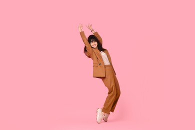 Photo of Beautiful young woman in stylish suit posing on pink background