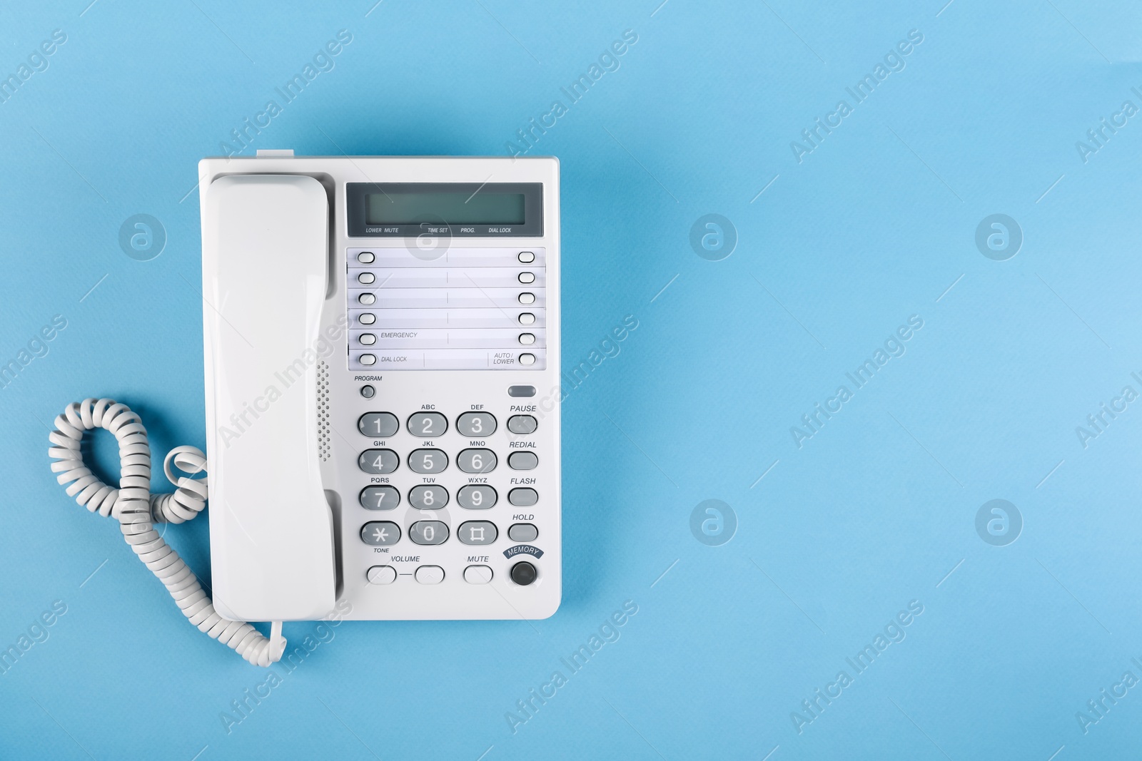 Photo of White telephone with handset on light blue background, top view. Space for text