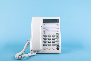 Photo of White telephone with handset on light blue background