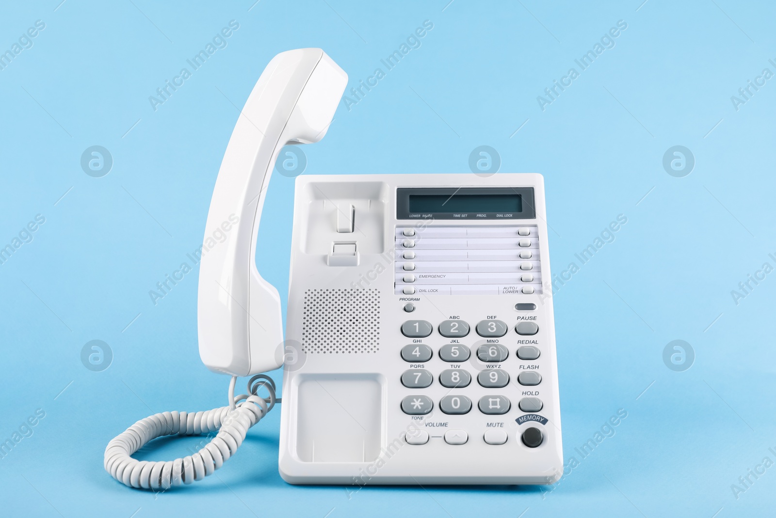 Photo of White telephone with handset on light blue background