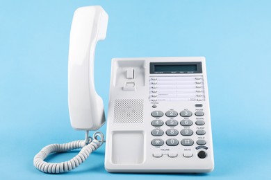 Photo of White telephone with handset on light blue background