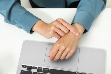 Photo of Carpal tunnel syndrome. Woman suffering from pain in wrist at desk, top view