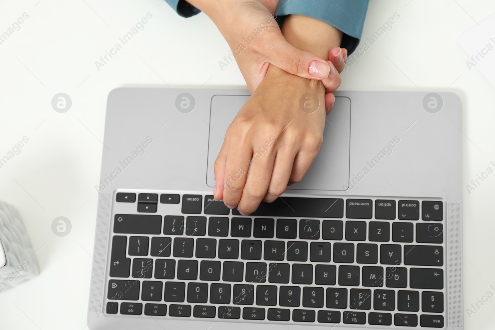 Photo of Carpal tunnel syndrome. Woman suffering from pain in wrist at desk, top view