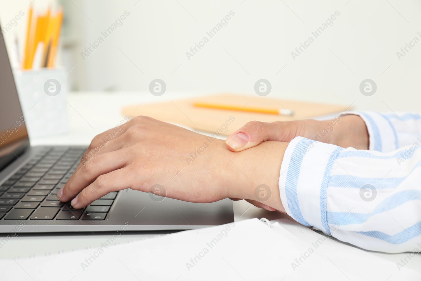 Photo of Carpal tunnel syndrome. Woman suffering from pain in wrist at desk, closeup