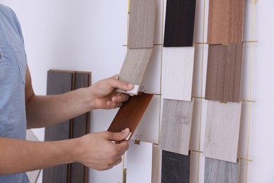 Photo of Man with different samples of wooden flooring indoors, closeup