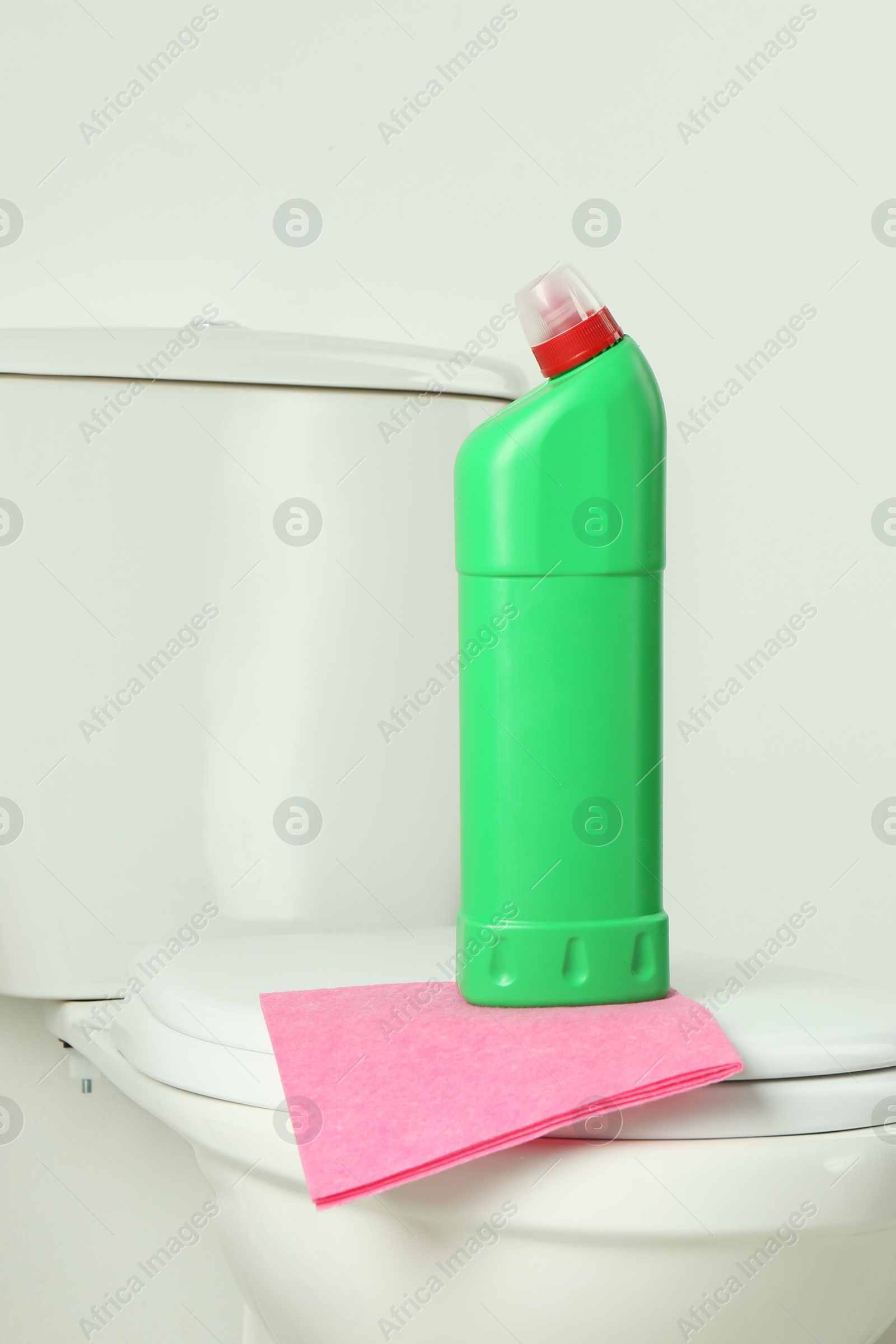 Photo of Detergent and rag on clean toilet in bathroom