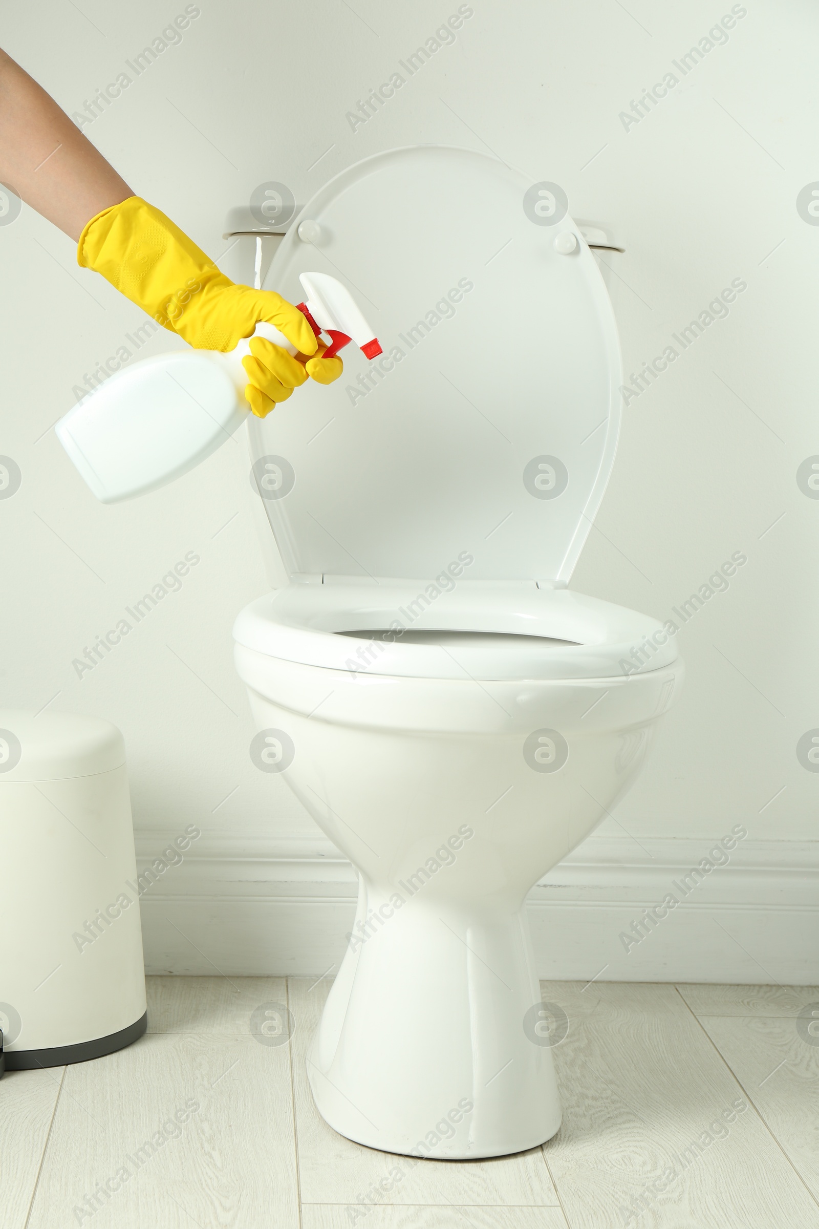 Photo of Woman with spray cleaning toilet seat in bathroom, closeup