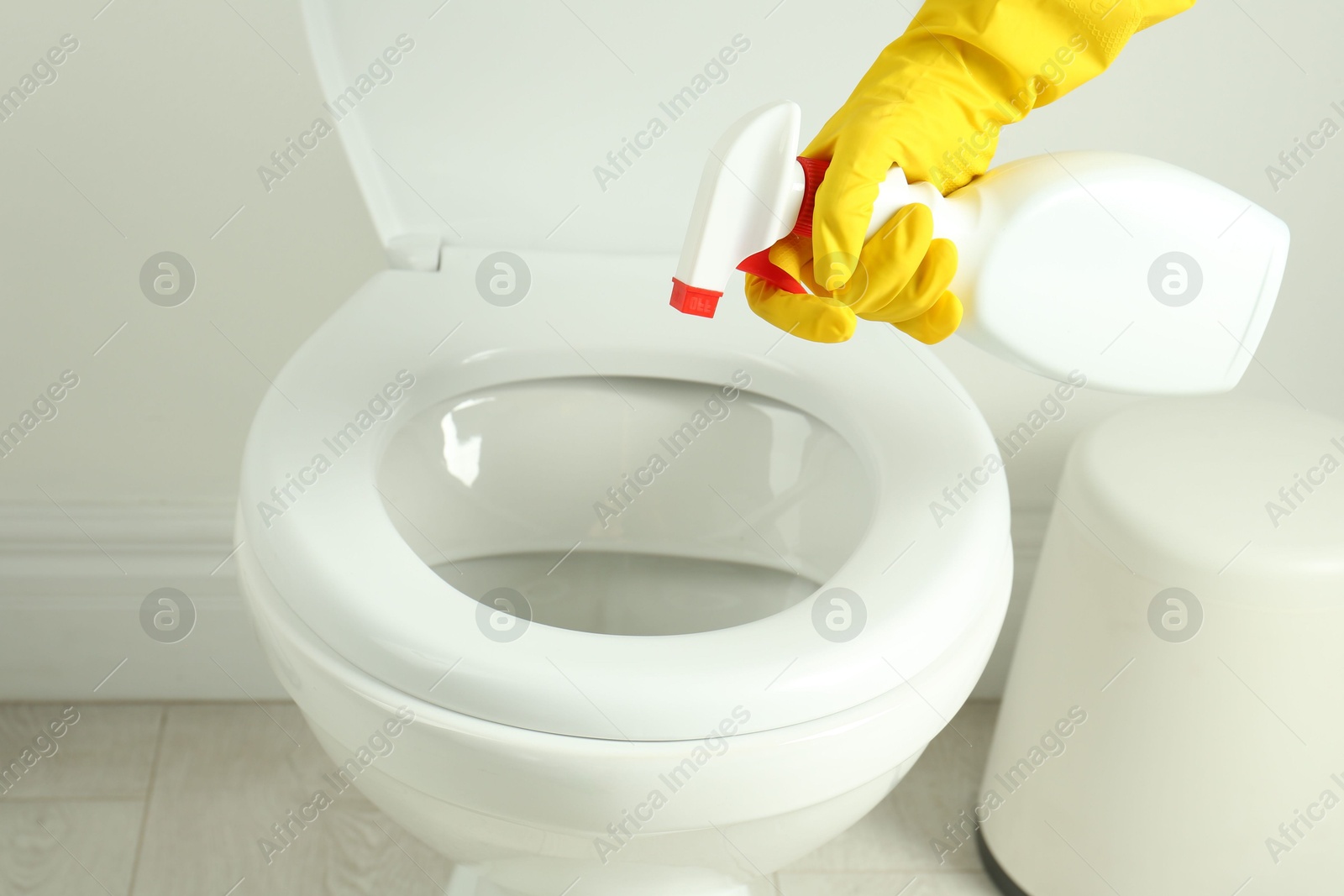 Photo of Woman with spray cleaning toilet seat in bathroom, closeup