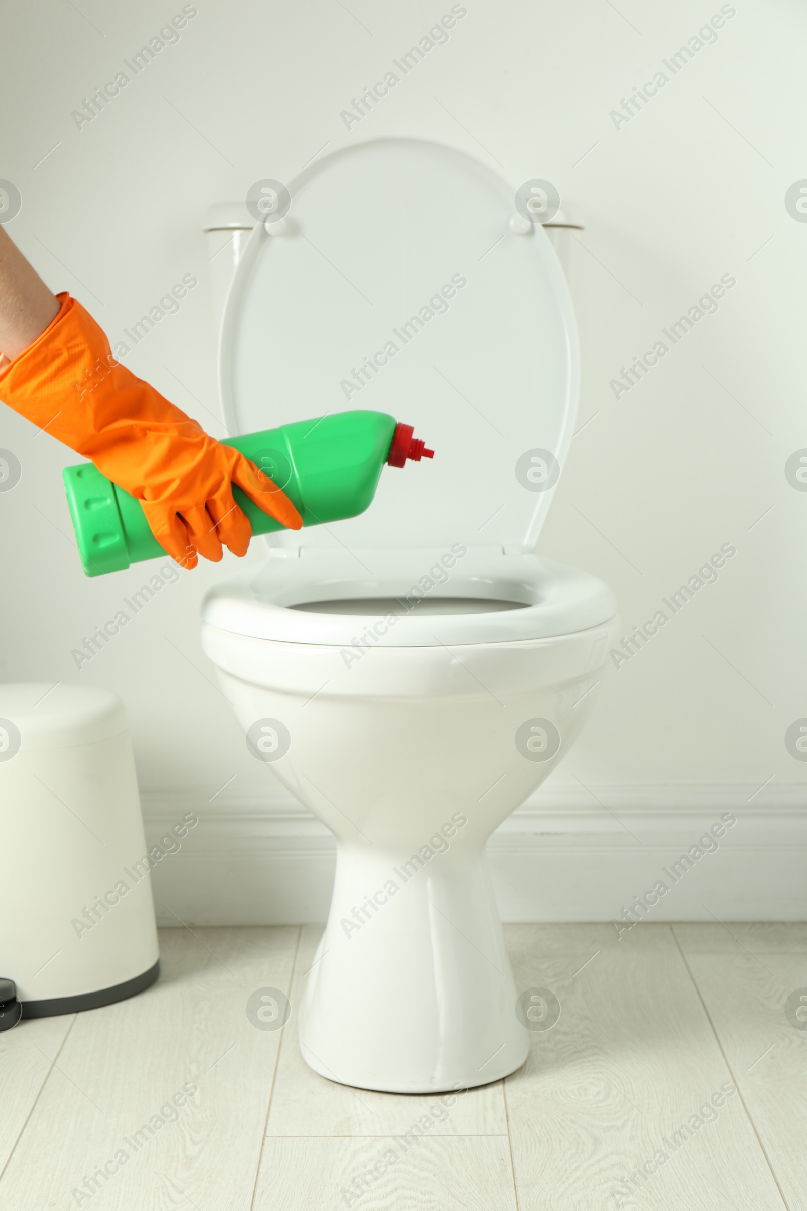 Photo of Woman with detergent cleaning toilet seat in bathroom, closeup