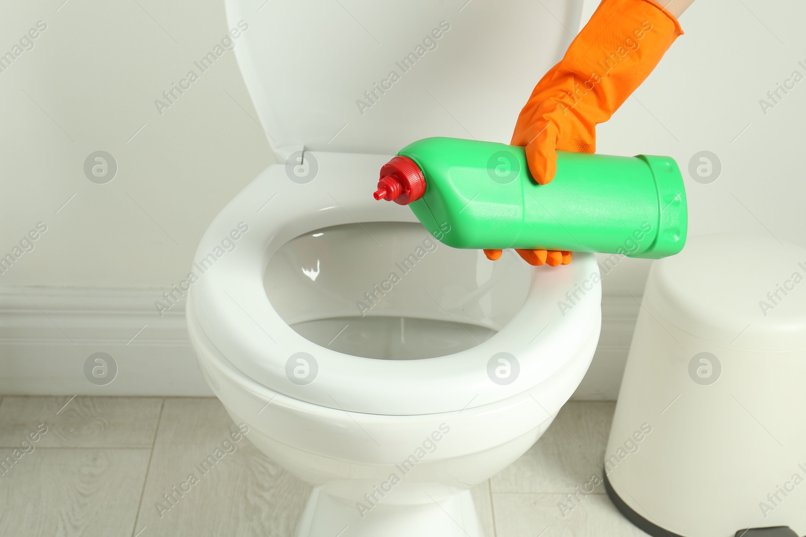 Photo of Woman with detergent cleaning toilet seat in bathroom, closeup