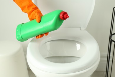 Photo of Woman with detergent cleaning toilet seat in bathroom, closeup