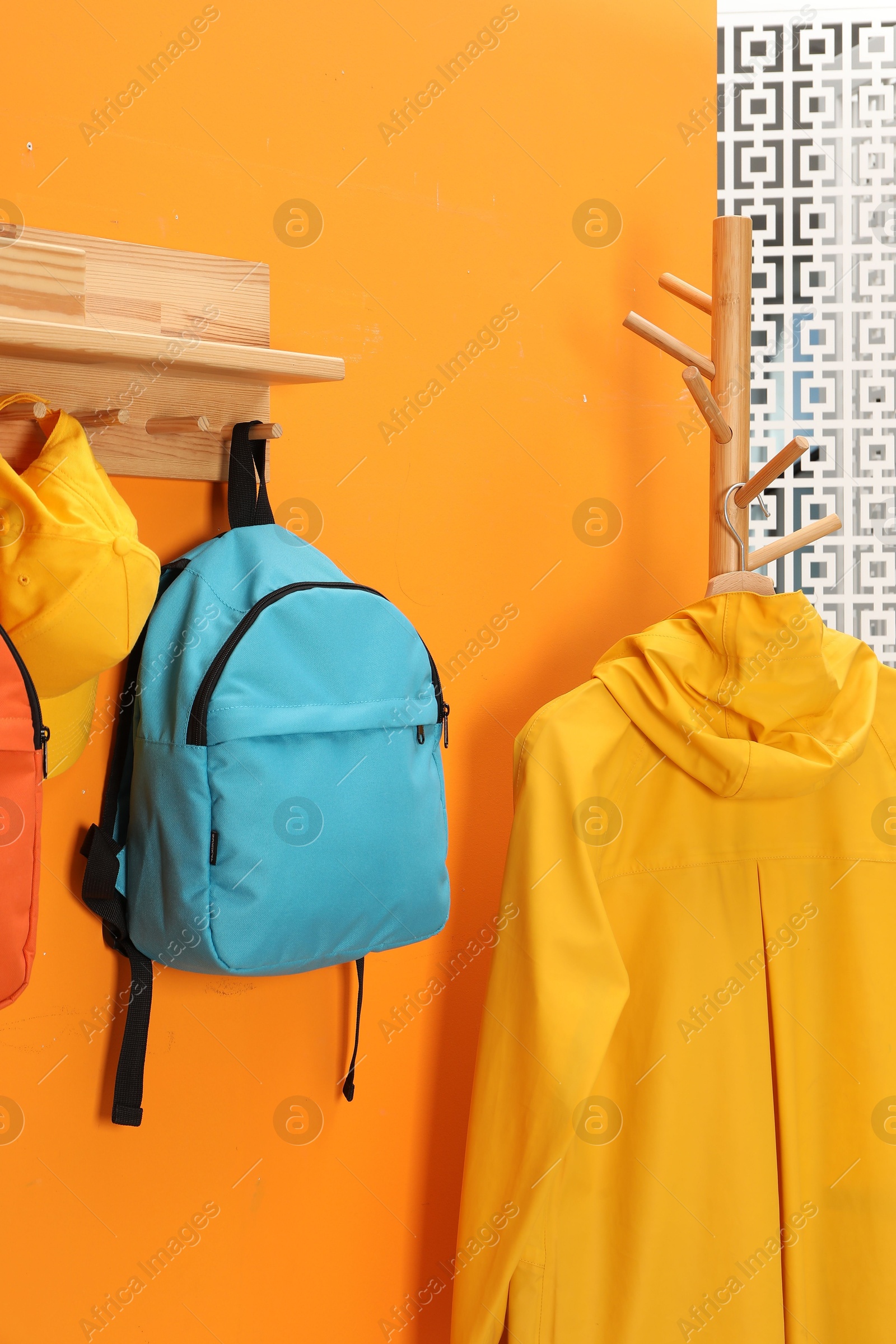 Photo of Bright backpacks, cap and coat near orange wall