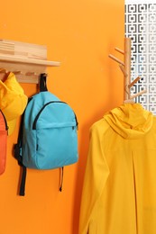 Bright backpacks, cap and coat near orange wall