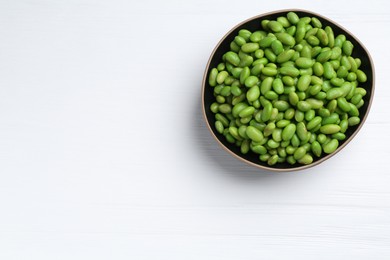 Photo of Fresh edamame soybeans in bowl on white wooden table, top view. Space for text