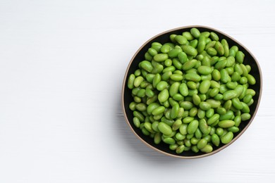 Photo of Fresh edamame soybeans in bowl on white wooden table, top view. Space for text