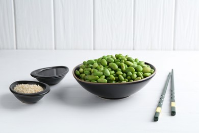 Photo of Fresh edamame soybeans, soy sauce and seeds on white wooden table