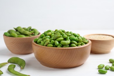 Photo of Fresh edamame soybeans, pods and seeds on white wooden table, closeup