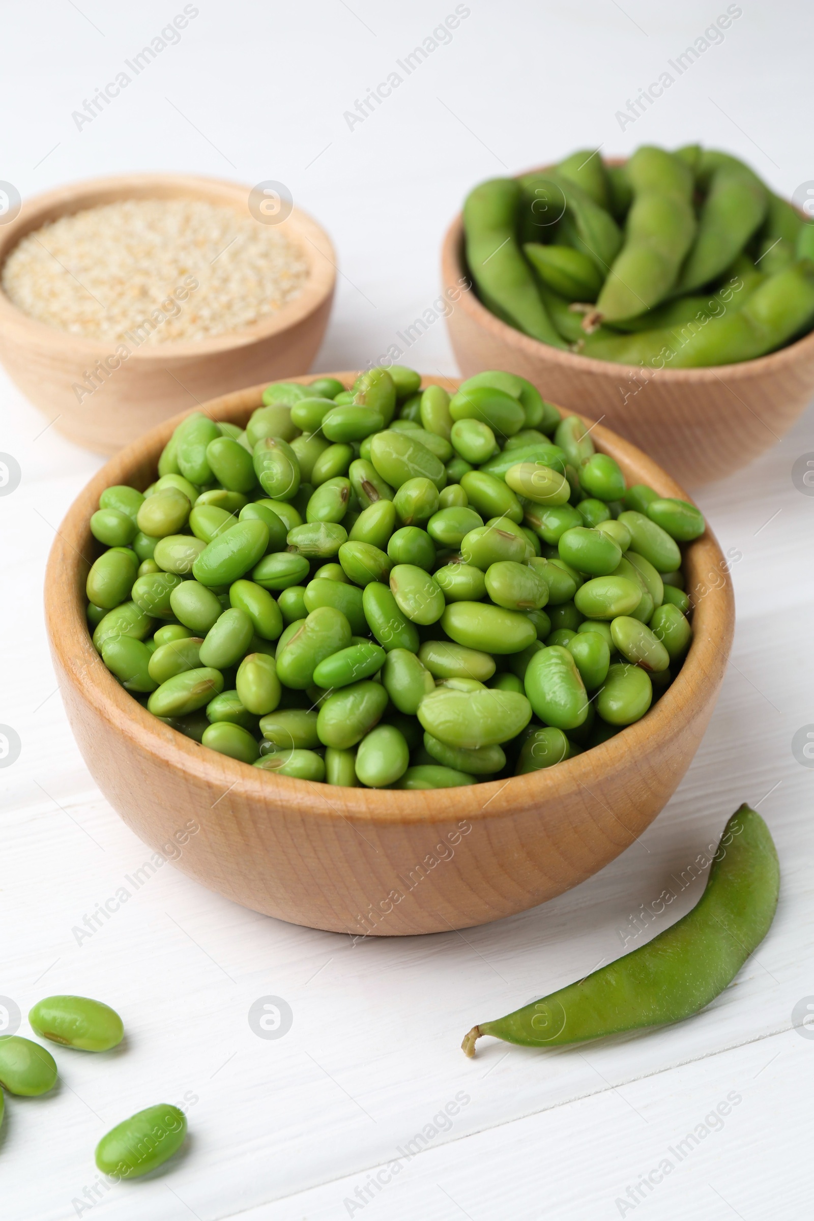 Photo of Fresh edamame soybeans, pods and seeds on white wooden table, closeup