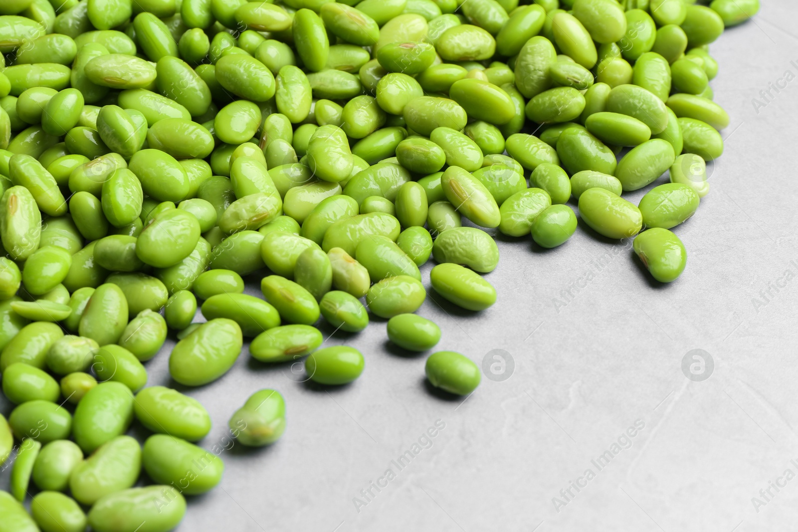 Photo of Fresh edamame soybeans on grey textured table, closeup